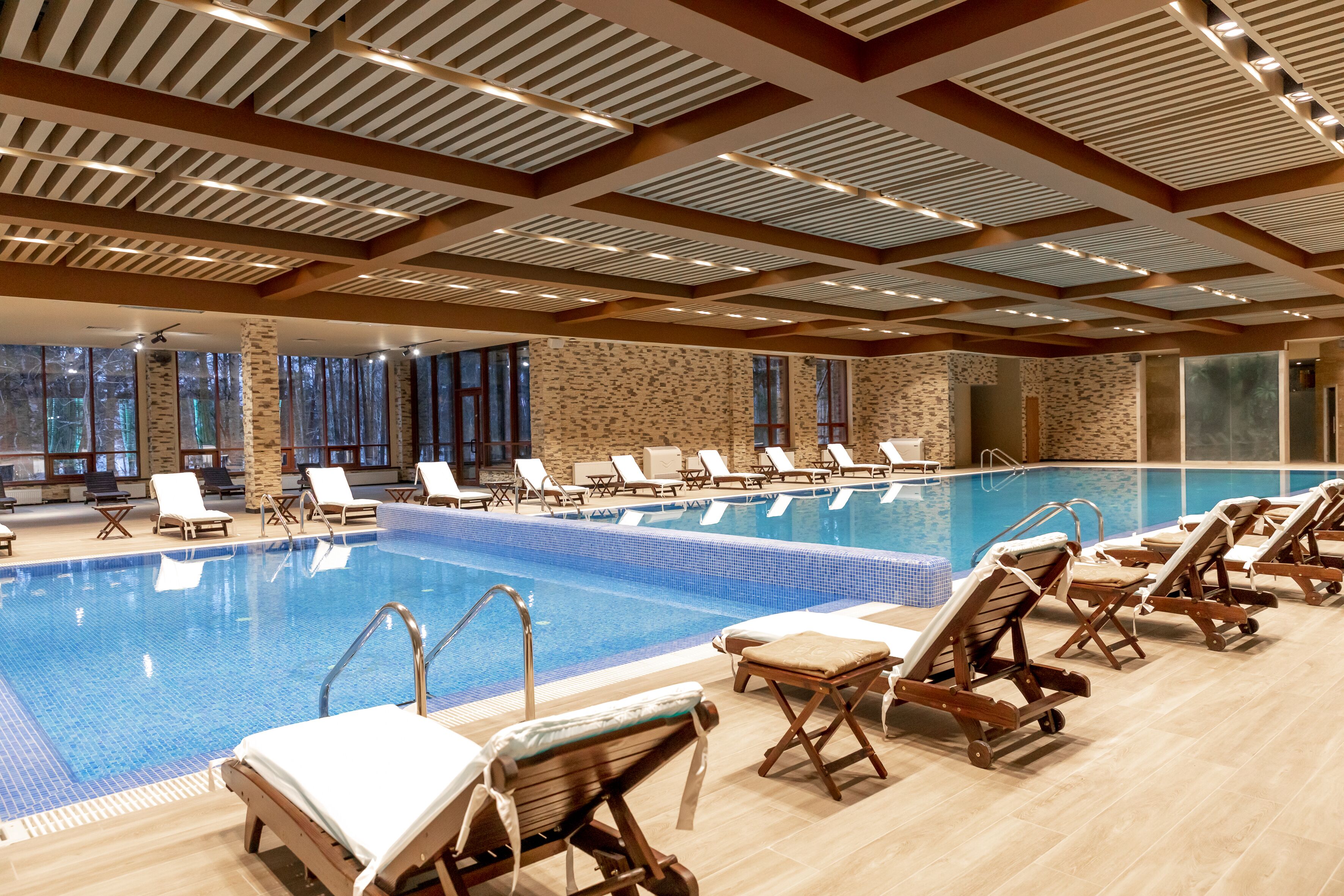 A large indoor swimming pool with multiple lounge chairs and a stone wall backdrop.
