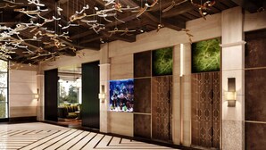 Un lobby moderno con suelo de patrón geométrico, elementos decorativos en el techo y una gran acuario.