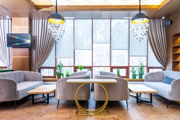 Un área de estar moderna con sofás, una mesa y un televisor.