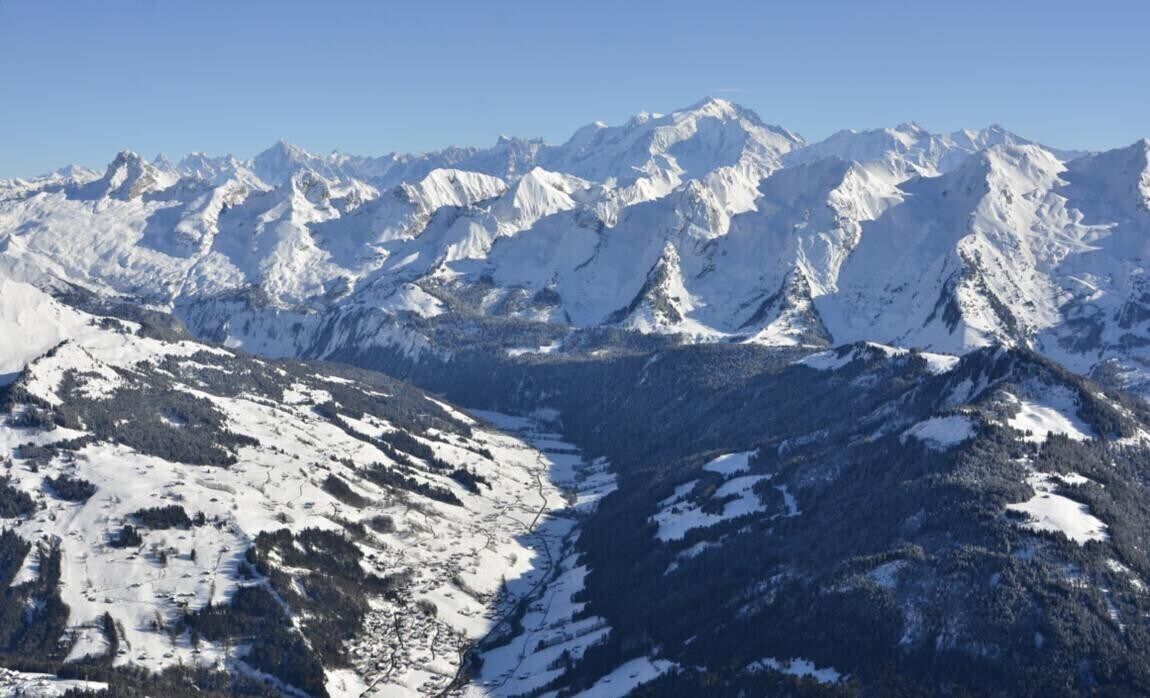 A snow-covered mountain range with a valley in the foreground.