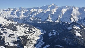 A snow-covered mountain range with a valley in the foreground.