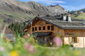 A wooden building with the sign "Les Congères" and a mountain backdrop.