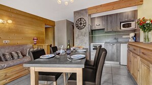 A modern kitchen with a dining area, wooden ceiling, and a clock on the wall.