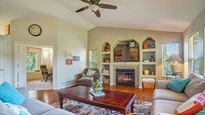 Un salon avec une cheminée, un ventilateur de plafond et un téléviseur.