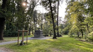 A serene park with a stone monument, a wooden pergola, and lush greenery. - Ferienwohnung König Georg (Wurzen)