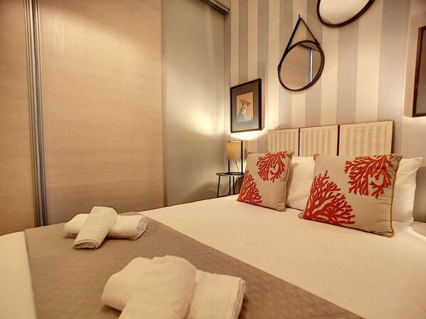 A hotel room with a large bed, striped wallpaper, a framed picture on the wall, and a bedside table with a lamp. - N&J - VEGA GIOFFREDO - Hyper center - Close sea (Niza)