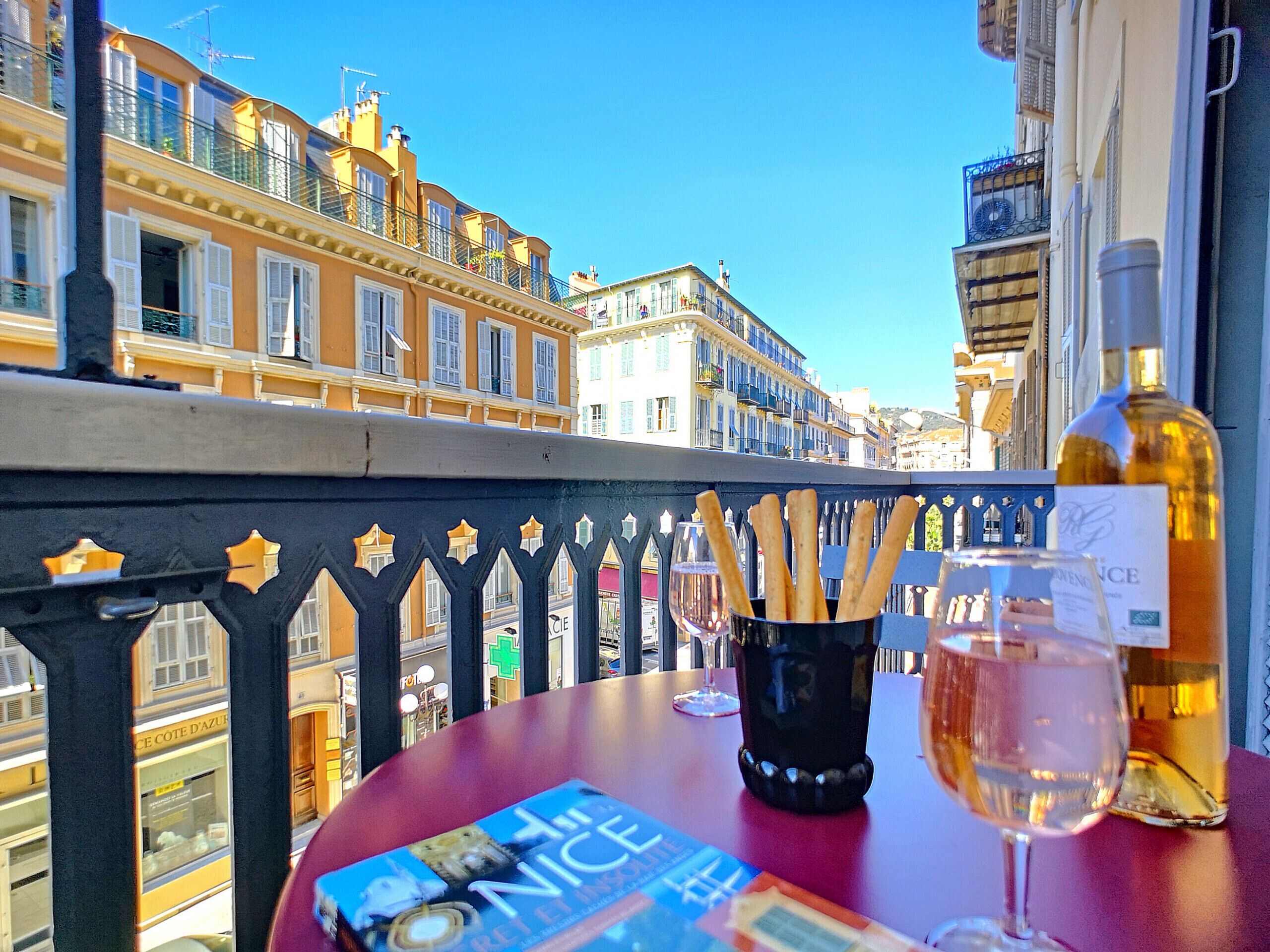 Un balcon avec une table, une bouteille de vin et un verre de vin.