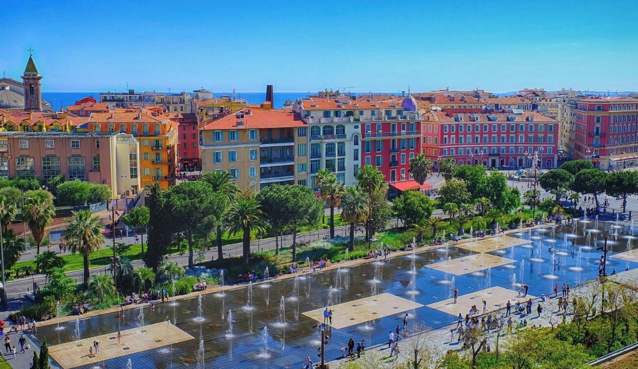 Una plaza con fuentes y edificios coloridos al fondo.