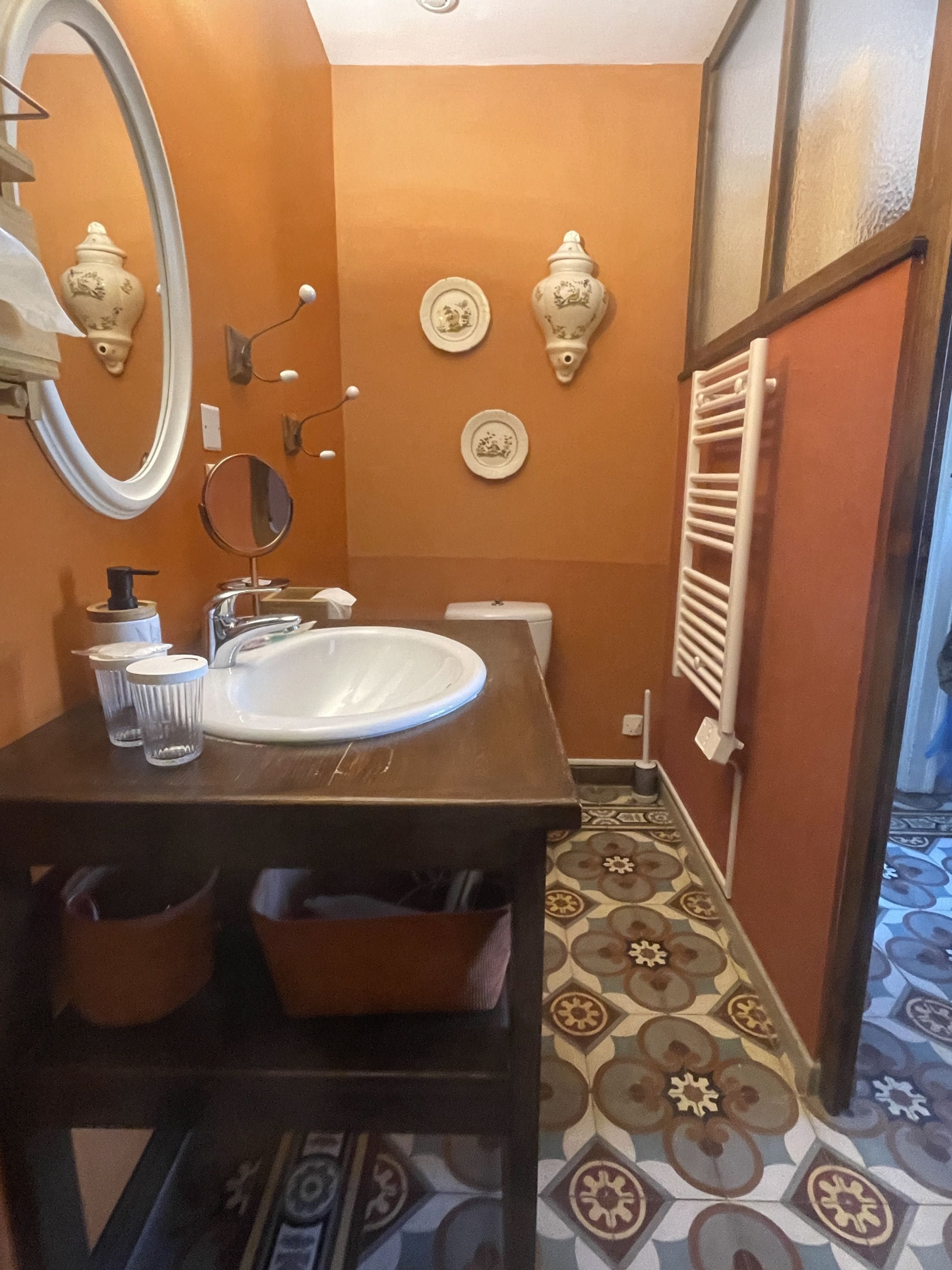 Un baño con lavamanos blanco, espejo y placas decorativas en la pared.