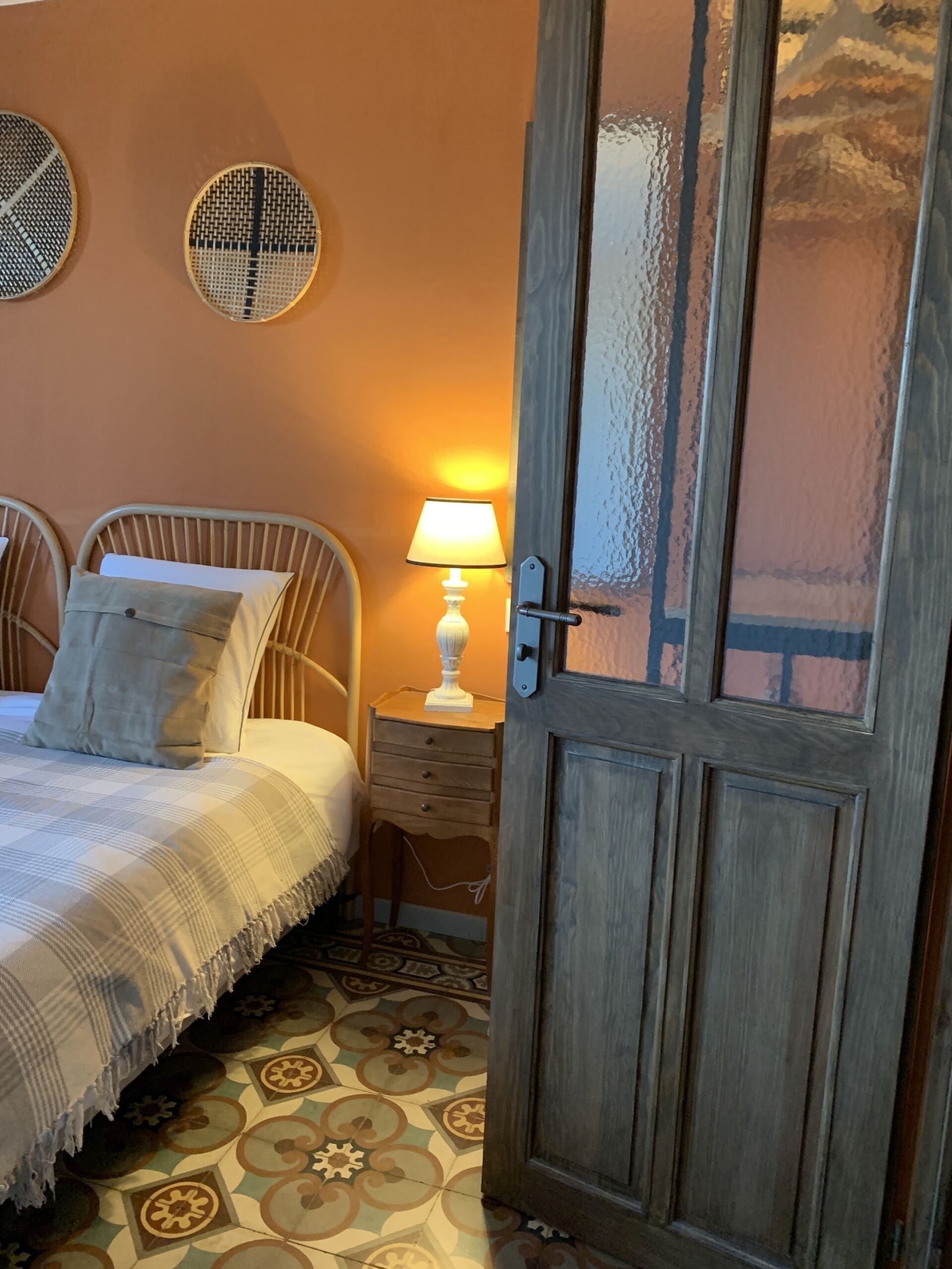 A bedroom with a bed, two bedside tables, a lamp, and a door.