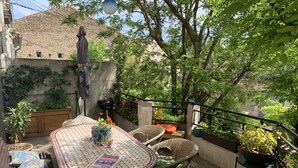 An outdoor patio with a round table, wicker chairs, and potted plants. - Lo Componaïro (Pouzols)