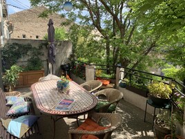 Un patio al aire libre con una mesa redonda, sillas de mimbre y plantas en macetas.