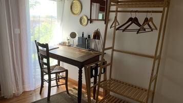 Une pièce avec une table en bois, des chaises, un portant à vêtements et des assiettes décoratives accrochées au mur.