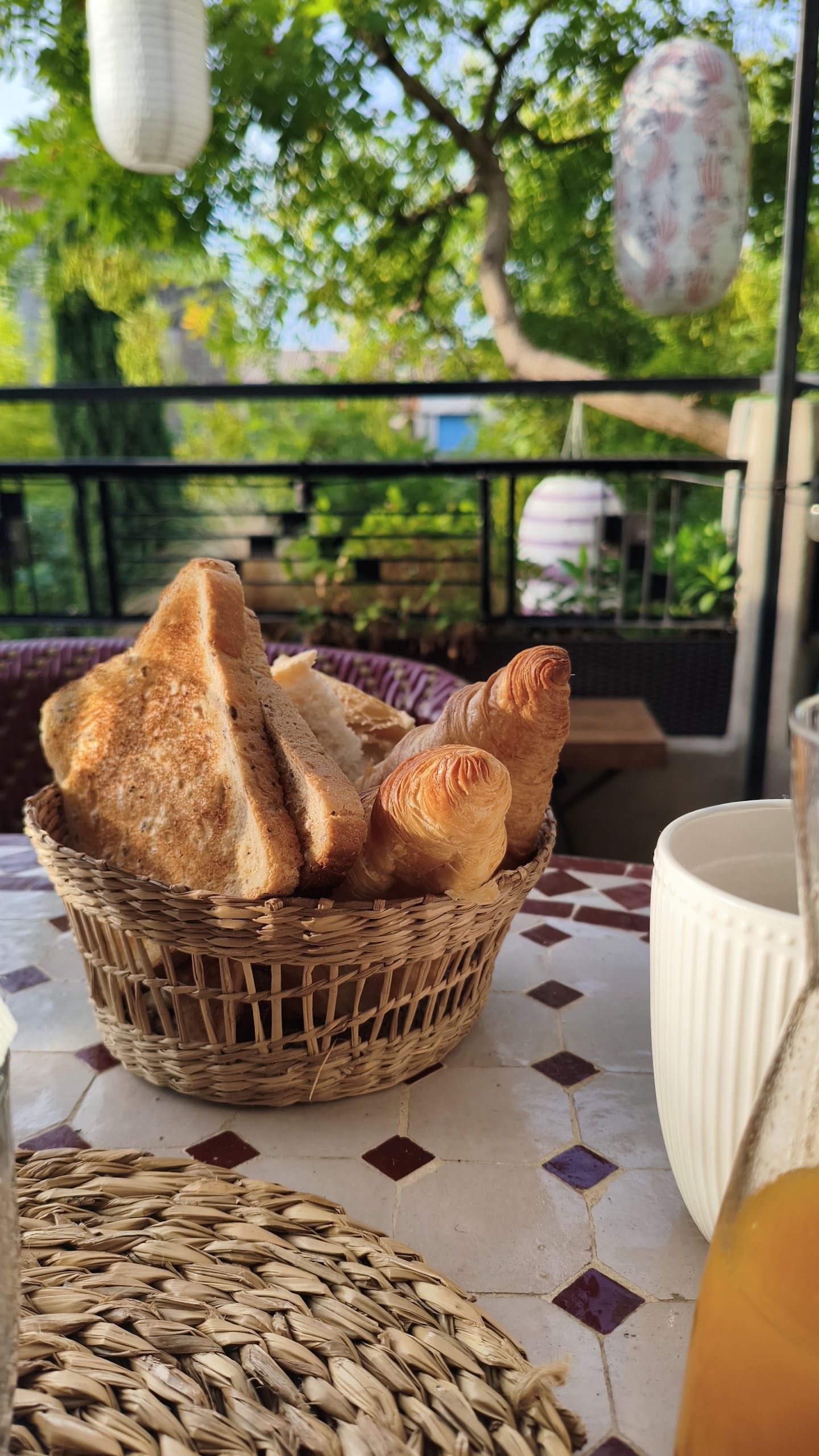 A wicker basket filled with bread on a table with a tiled floor.
