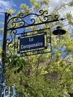 Un letrero con el texto "Lo Componaire" montado sobre una estructura metálica decorativa.