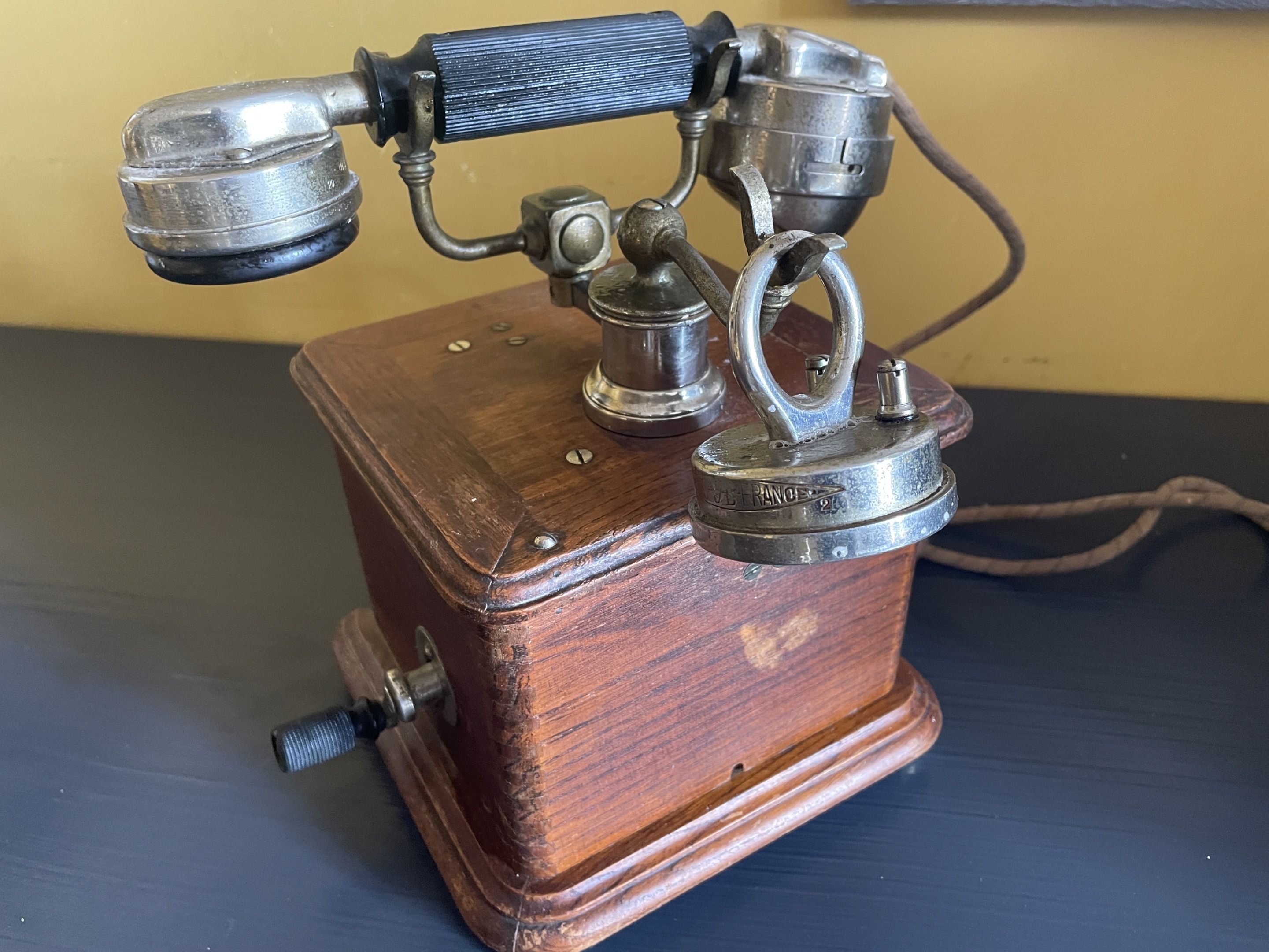 A vintage telephone with a wooden base and metal components.