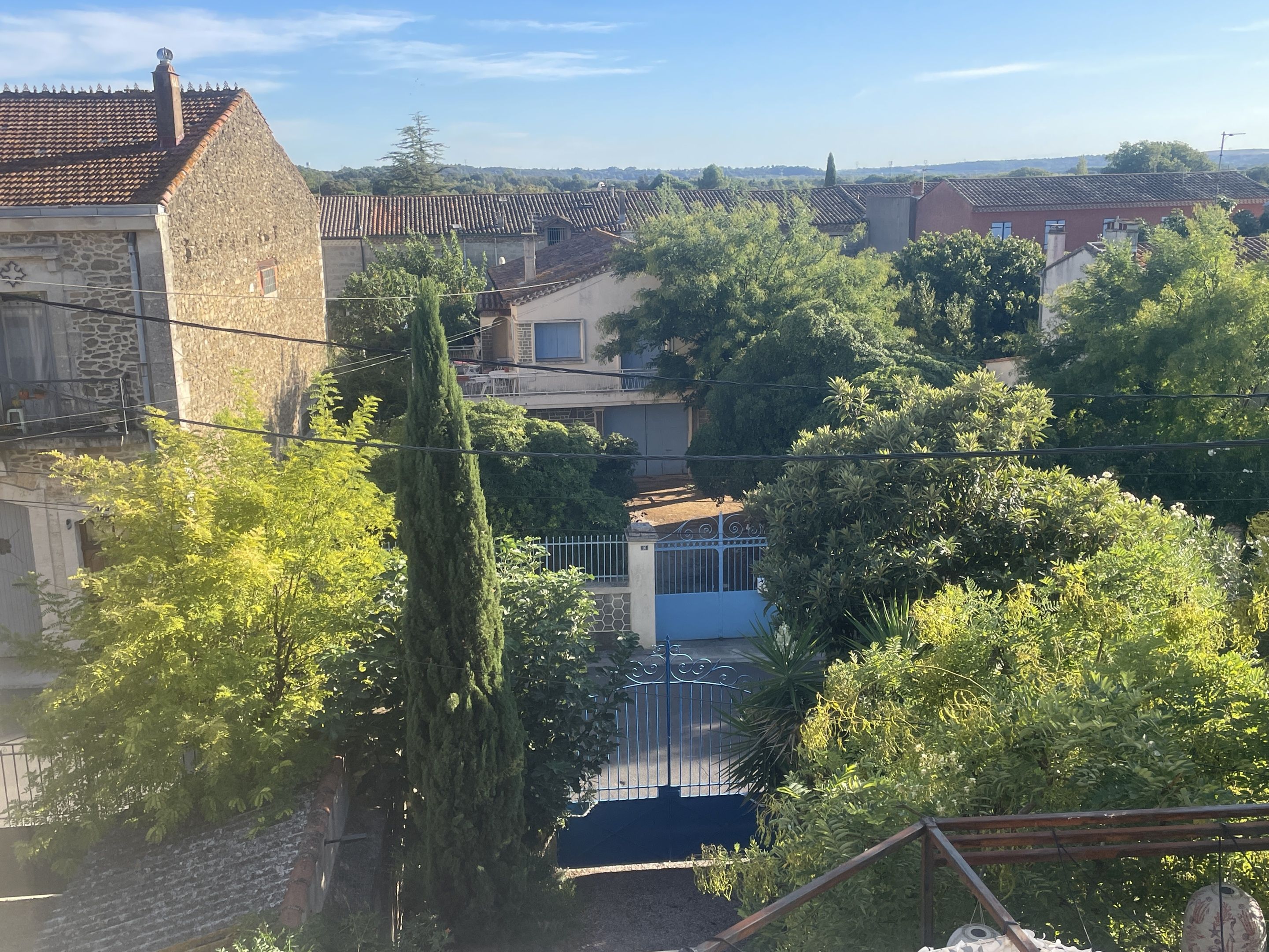 Un quartier résidentiel avec des bâtiments en pierre, un grand arbre et une maison bleue.