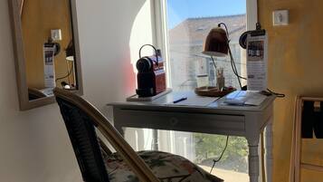 A room with a desk, chair, and a window with a view of a building.
