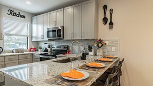 A modern kitchen with a central island, stainless steel appliances, and a view of the outside.