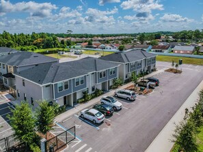 A residential area with modern houses, a parking lot, and a clear sky.