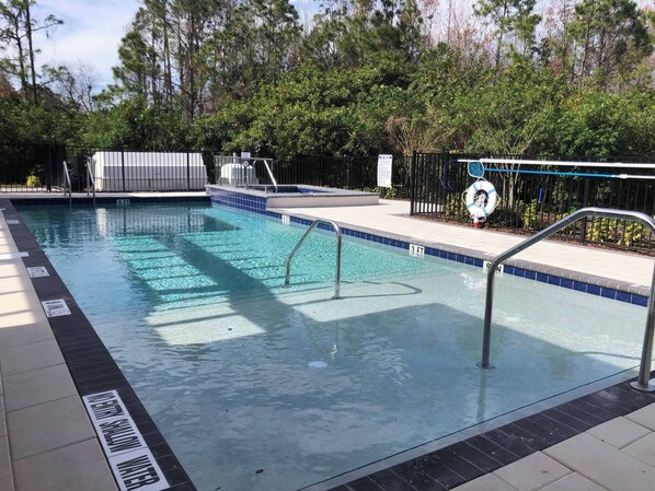 A swimming pool with clear blue water, a metal ladder, and a lifeguard stand.