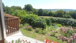 Un balcón con vistas a un jardín y viñedos.