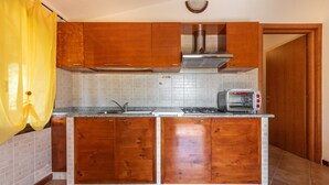 Une cuisine avec des meubles de rangement en bois, un pare-feu en carreaux, une cuisinière encastrée et un grille-pain.