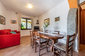 A dining area with a wooden table, chairs, and a red sofa. - Holiday Apartment "Villa Mallus" with Mountain View (castiadas olia speciosa)