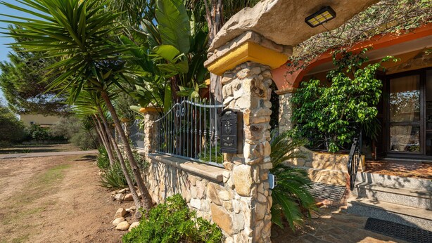 A stone building with a stone staircase leading to a door, surrounded by tropical plants. - Apartment "Casa Mallus" With Mountain View, Balcony, Garden, Terrace & Grill (castiadas olia speciosa)