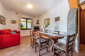 A dining area with a wooden table, chairs, and a red sofa.