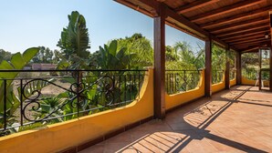 A covered outdoor area with a tiled floor, metal railing, and yellow walls. - Apartment "Casa Mallus" With Mountain View, Balcony, Garden, Terrace & Grill (castiadas olia speciosa)