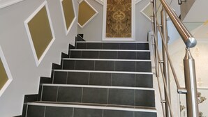 Una escalera con baldosas negras y una pared decorada con detalles dorados.