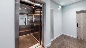 An elevator with a digital display, a vent, and a door with a number. - Aptel East (London)