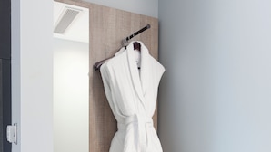 A walk-in closet with a wooden vanity, a hanging robe, and shelves with shoes and a shoe rack. - Aptel East (London)
