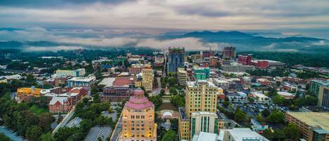 A cityscape with a mix of historic and modern buildings, a prominent dome structure, and a mountainous backdrop.