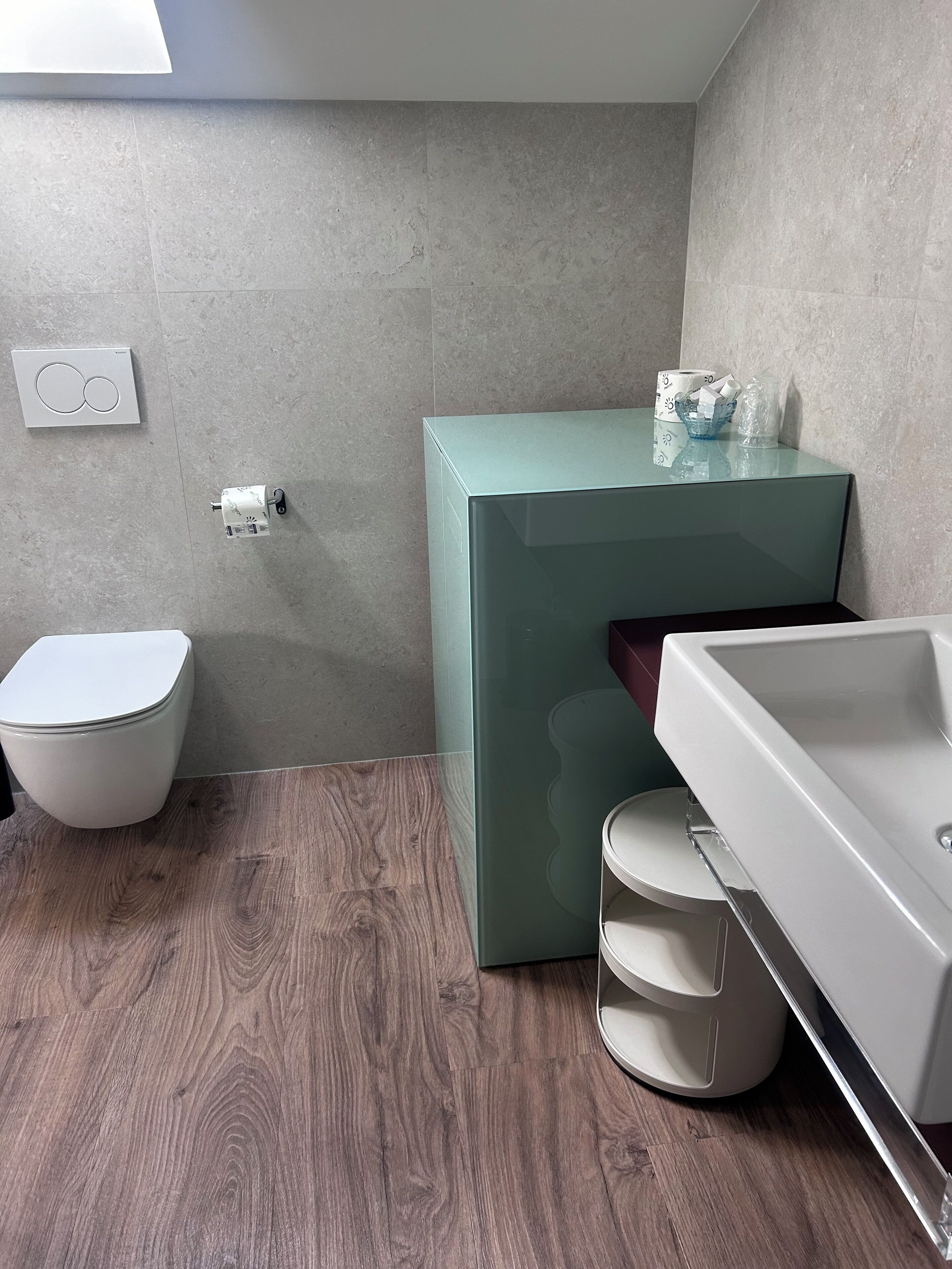 Ein modernes Badezimmer mit Toilette, einem grünen Schrank und einem weißen Waschbecken.