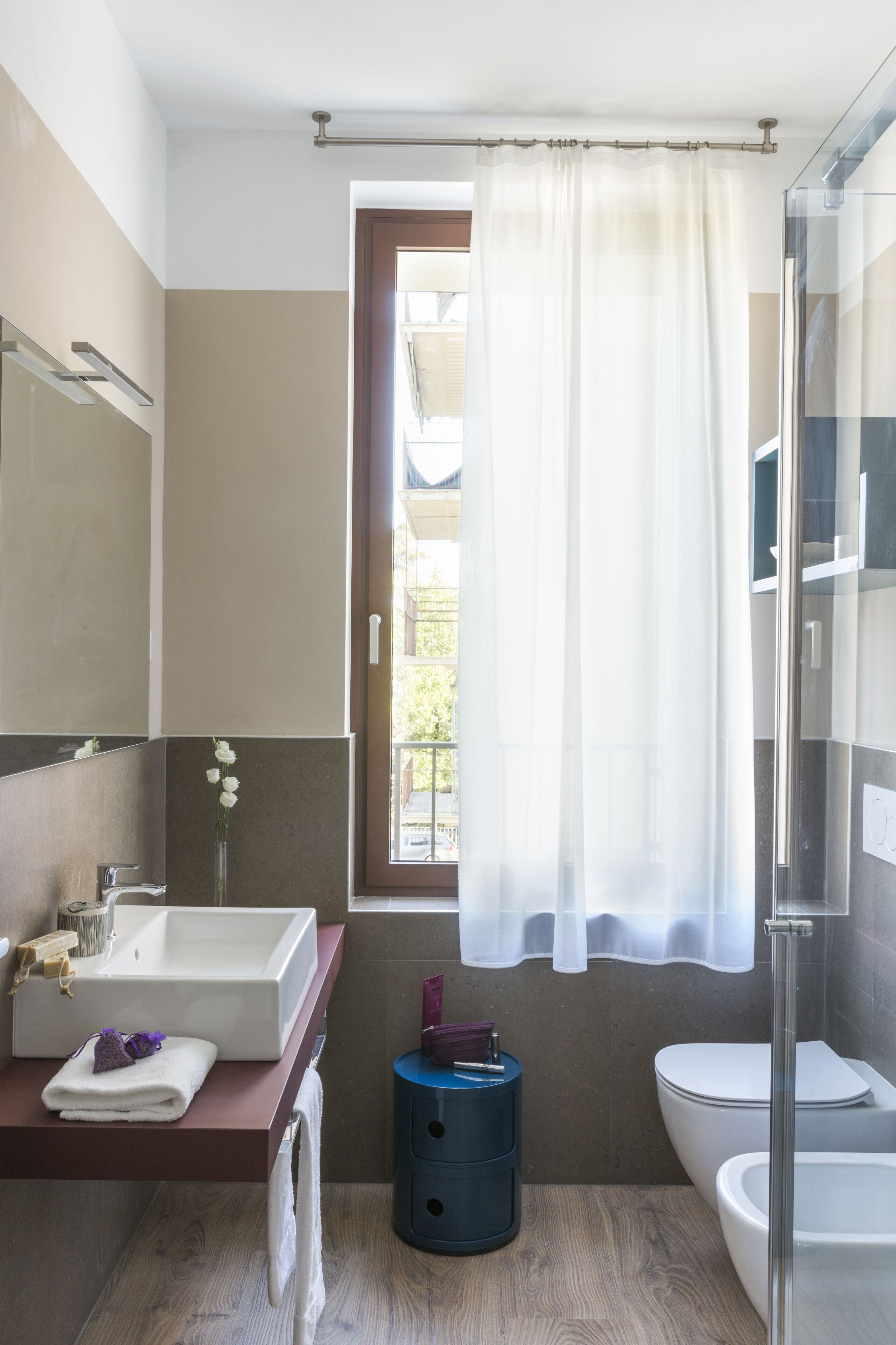 Une salle de bain moderne avec une grande fenêtre, un lavabo, des toilettes et une douche.