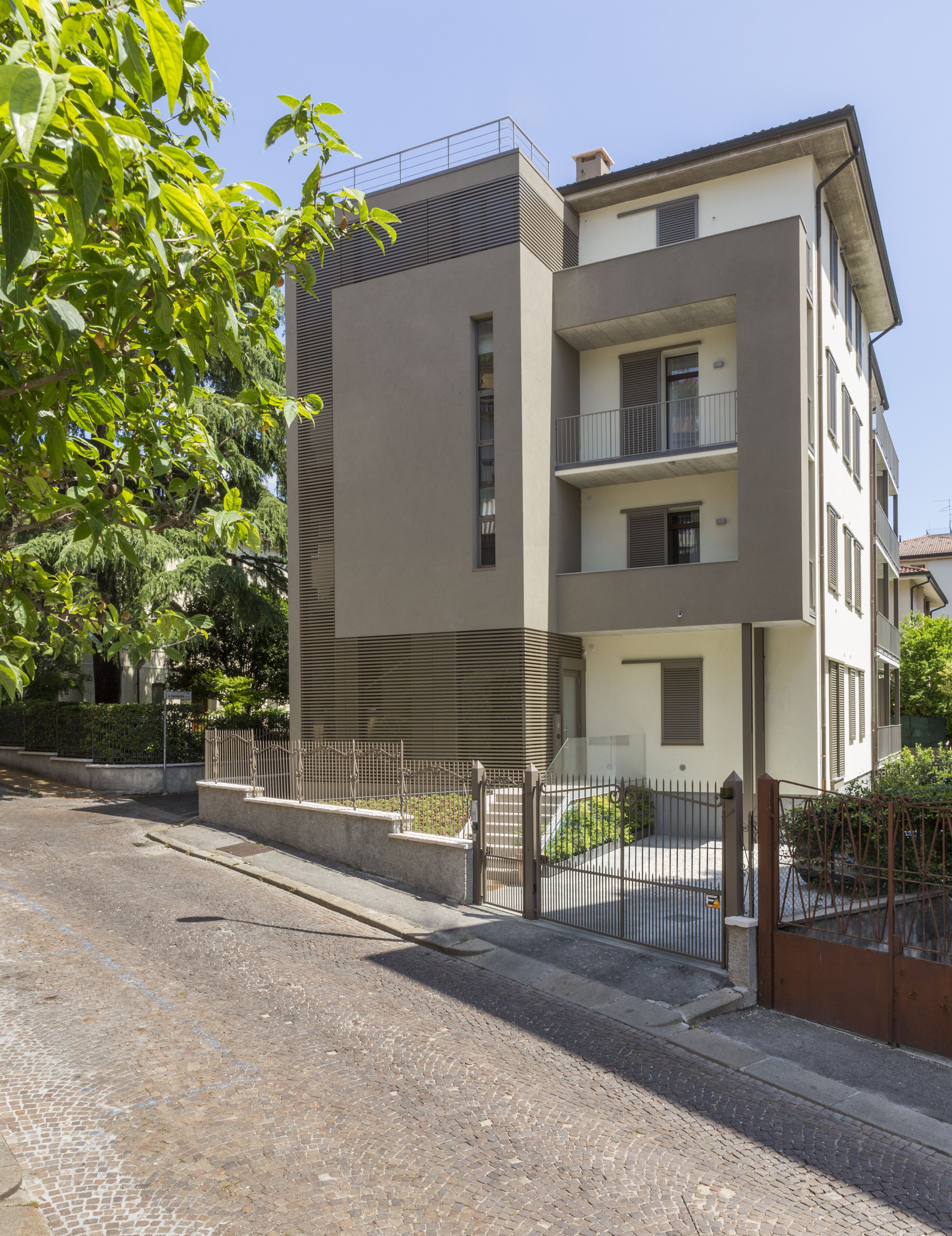 A modern multi-story residential building with a flat roof, balconies, and a gated entrance.