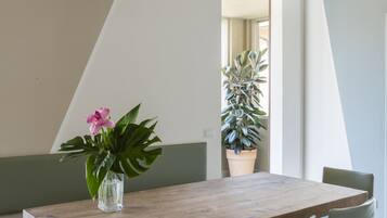 A modern dining area with a wooden table, clear glass chairs, a potted plant, and a bench.