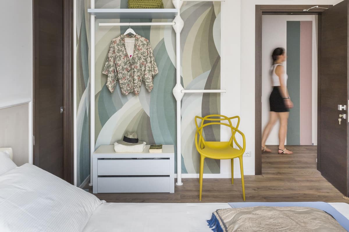Une chambre à coucher moderne avec un lit, une armoire et une chaise jaune.