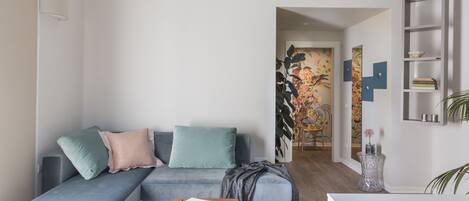 Una sala de estar moderna con un sofá gris, una mesita de madera y una zona de cocina con estufa a gas.