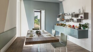 A modern kitchen with a wooden dining table, a built-in island with shelves, and a view of the outdoors. - San Leonardo Suites (Verona)
