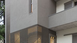 A modern building with a staircase leading to a balcony, surrounded by a landscaped garden area. - San Leonardo Suites (Verona)
