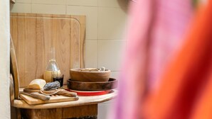 A kitchen counter with a wooden cutting board, a glass bottle, a bowl, and a red plate. - Entire house in the countryside with garden and sea view (Pesaro)