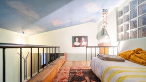 A bedroom with a bed, a window with curtains, a painting on the wall, and a staircase with a railing. - Entire house in the countryside with garden and sea view (Pesaro)