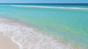 A beach with clear turquoise water and gentle waves.