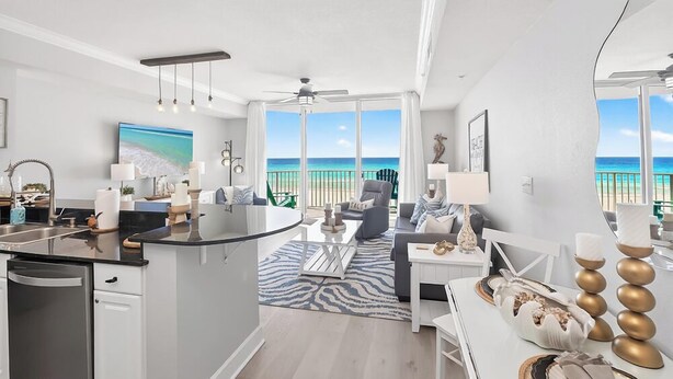 A modern living room with a kitchen, large windows, and a view of the beach.