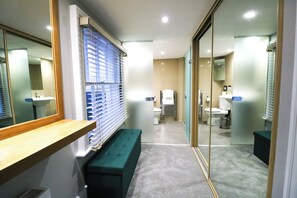 A modern bathroom with a bench, a mirror, and a glass partition.