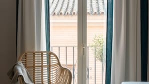 Una habitación con puerta de cristal corrediza que da a un balcón con tejado de baldosas.