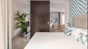 Una habitación de hotel moderna con una cama grande, un comedor y una sala de estar.